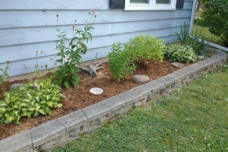 A mulched bed with a border made out of stone paver blocks.